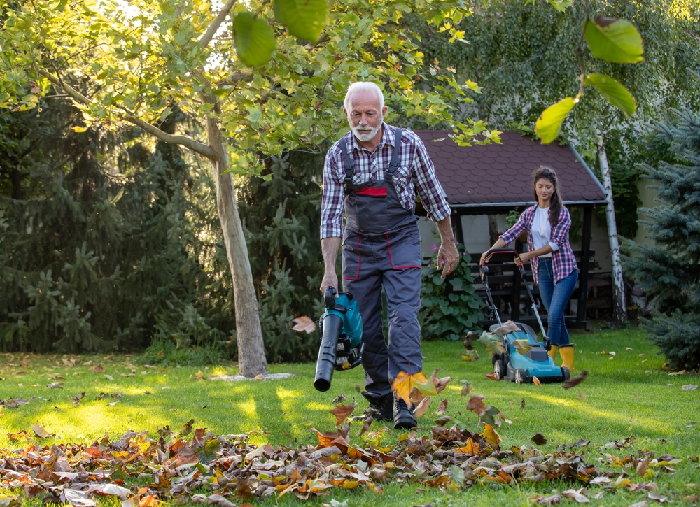 Senior,Man,In,Overall,Working,In,Garden,With,Leaf,Blower